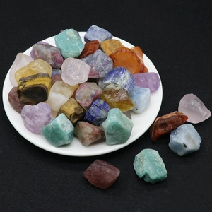 Assorted natural crystal raw stones including amethyst and tiger eye in a white ceramic bowl