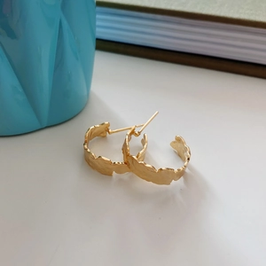 Detailed view of gold C-shaped earrings featuring a vintage irregular wavy edge design