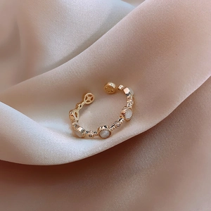 Macro shot of gold adjustable ring with white opal stone and pavé rhinestones on silk
