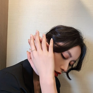 Close-up of a minimalist gold ring with white decorative stones on a female hand