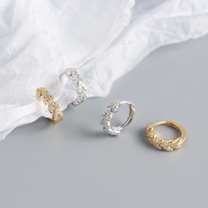 Macro view of gold and silver leaf-shaped hoop earrings with shimmering zircons