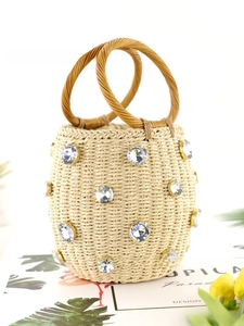 Close-up of beige woven straw bucket bag featuring sparkling rhinestone embellishments