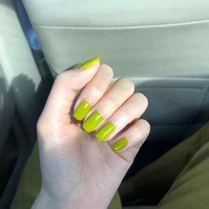 Uñas postizas cortas verde aguacate brillante mostradas como manicura en la mano