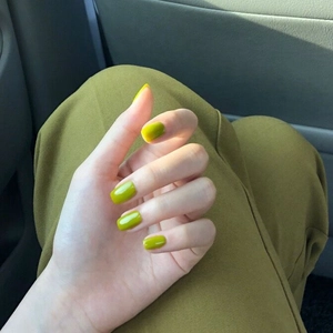 Primer plano de uñas postizas largas y redondeadas en color verde aguacate