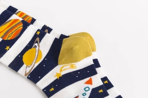 Detail of space-themed cotton socks featuring rockets, planets, and stars on striped fabric