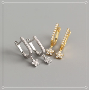 Detail of S925 sterling silver U-shaped earrings with gold and silver flower pendants