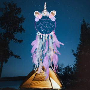 Dreamy unicorn dream catcher with pink flowers and purple feathers against a starry night sky