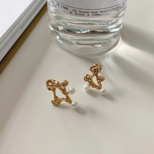 Detail of irregular gold lava textured silver earrings with elegant white pearls