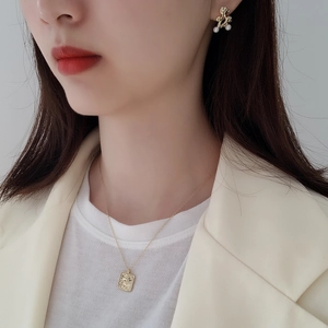 Detail of vintage gold portrait necklace and irregular pearl earrings on model