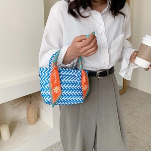 Blue and white woven straw tote bag with decorative orange silk scarf handle wrap