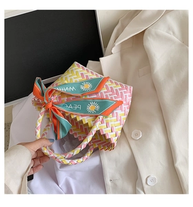 Detail showing handwoven pink and yellow striped straw bag with decorative daisy silk scarf