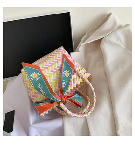 Detail of woven straw bag with colorful geometric patterns and decorative floral silk scarf