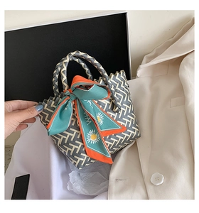 Detail of woven tote bag featuring geometric patterns and colorful silk scarf handle