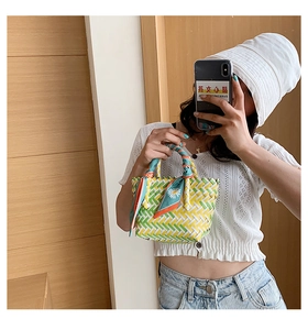 Detail of colorful woven tote bag with green floral scarf wrap on the handle