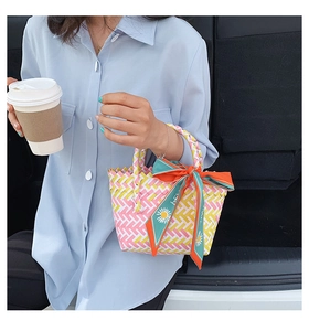 Detail of colorful woven tote bag with silk scarf handle decoration for summer