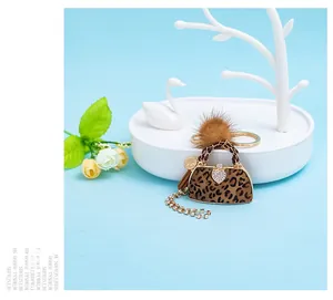 Detail of leopard print handbag keychain with heart rhinestone and brown fur pom pom charm