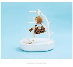Detail of leopard print handbag keychain with plush fur ball and tassel on a stand