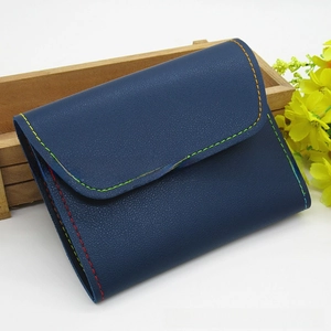 Detail of navy blue leather case with colorful rainbow stitching and textured finish