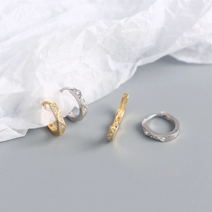 Artistic layout of geometric faceted gold and silver earrings with zircon inlay details