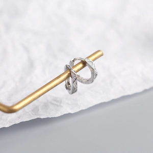 Detail view of S925 sterling silver hoop earrings with diamond accents on a gold stand