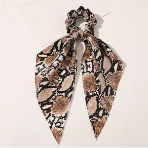 Detail of satin hair scrunchie with long ribbons in realistic brown python snake print