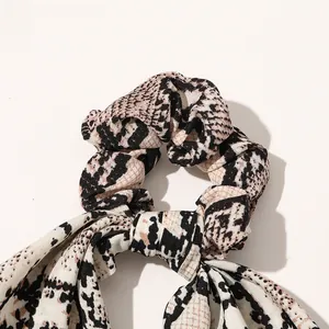 Macro shot of satin scrunchie with long ribbons and fashionable python animal print texture