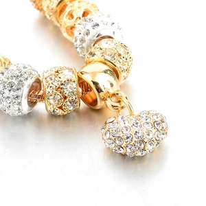 Macro shot of gold and silver beaded bracelet featuring a sparkling heart charm pendant