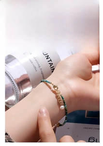 Detail of beaded turquoise bracelet with freshwater pearl charm and golden clasp