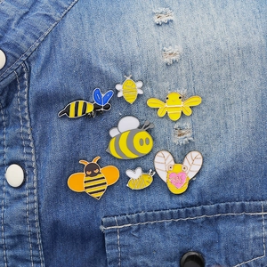 Set of 7 cartoon bee enamel pins in yellow and black on denim shirt pocket