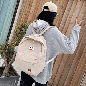Corduroy backpack in beige with 3D eye decor and embroidery detail on back of model