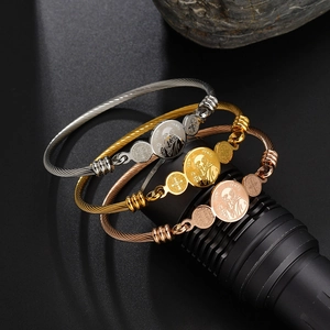 Macro detail of three-tone steel cable bracelets with engraved St. Benedict religious medals