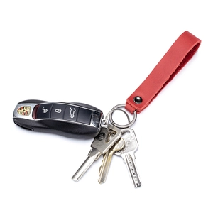 Red leather car keychain strap with metal ring and Porsche key on white background