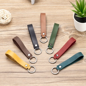 Genuine leather car keychains in multiple colors arranged on a wooden desk with metal rings
