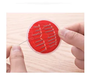 Detailed view of hands opening the round red sewing needle storage case and metal needles