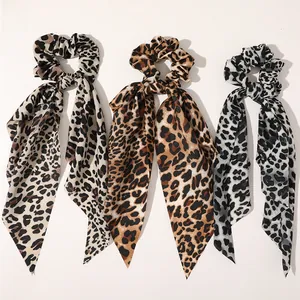 Close-up of leopard print satin hair scrunchies with long ribbons in beige and brown