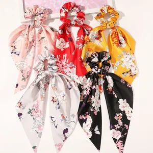 Flat lay of satin floral bow scrunchies in pink, red, yellow, grey and black colors