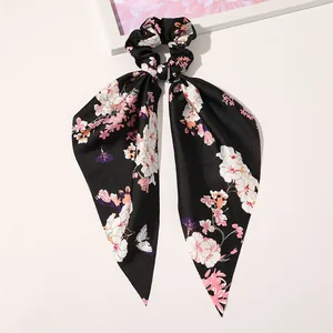 Detailed shot of black satin scrunchie with floral butterfly print and long ribbon bow