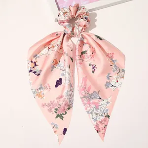 Detailed view of pink floral satin scrunchie with long ribbons on white background