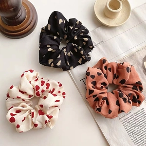 Three scrunchies with heart patterns on a newspaper background in an INS style lifestyle setting