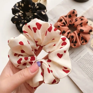 Detailed view of three soft fabric scrunchies with elegant heart patterns in various colors