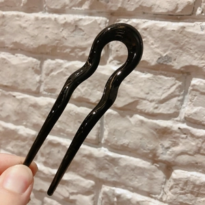 Detailed view of a sleek black wave-shaped U-pin resin hair fork for elegant hairstyling