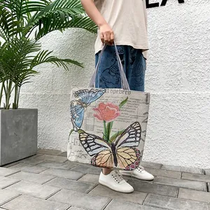 Close-up of ethnic canvas tote bag with butterfly embroidery and striped handles
