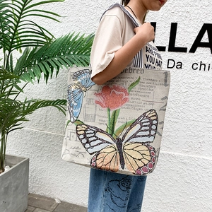 Detail of artistic canvas tote bag featuring vibrant butterfly and red tulip prints