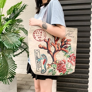 Outdoor shot of a large canvas tote bag with coral and rose prints on a female model