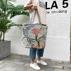 Detail of canvas tote bag with butterfly prints and black-white striped handle