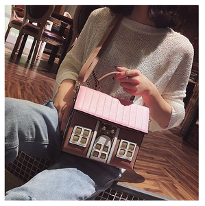 Detailed macro shot of creative house-shaped crossbody bag with pink roof and gold hardware