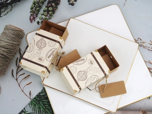 Vintage mini suitcase favor boxes in beige cardboard with rustic luggage tags on a plate
