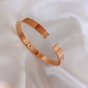 Detail of rose gold stainless steel hinged bangle on elegant white silk background
