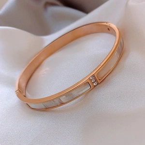 Detail of rose gold bangle with white shell inlay and three vertical sparkling zircons