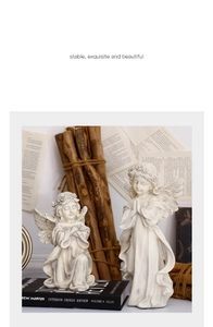 Detailed close-up of two vintage white resin angel sculptures on antique books and wood